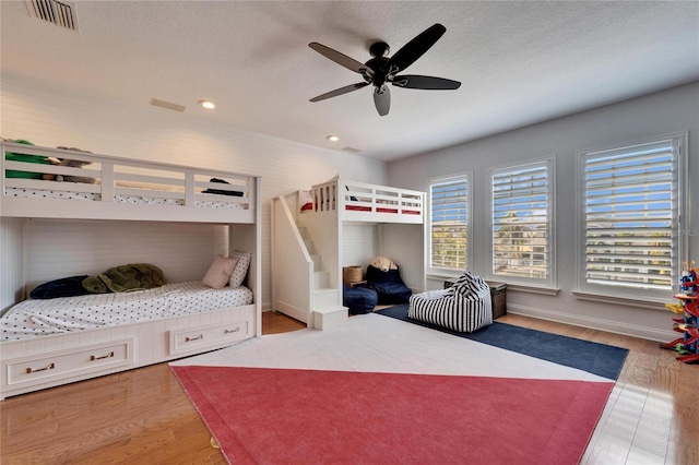 bedroom with ceiling fan, light wood-type flooring, and a textured ceiling