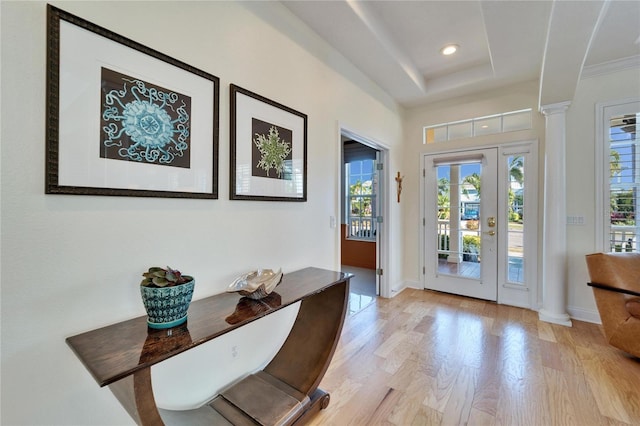 entryway featuring light hardwood / wood-style floors, decorative columns, and a tray ceiling