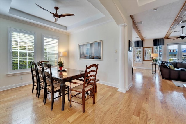 dining area featuring light hardwood / wood-style floors, ornate columns, ceiling fan, a tray ceiling, and ornamental molding