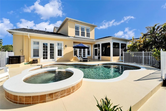 rear view of property featuring a pool with hot tub, french doors, a patio area, and a sunroom