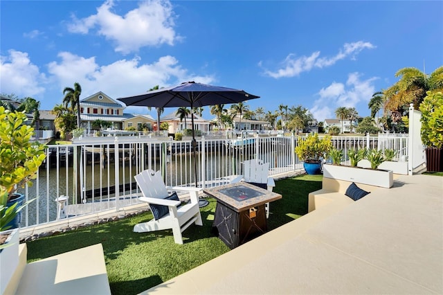 view of dock with a yard, a water view, and an outdoor fire pit