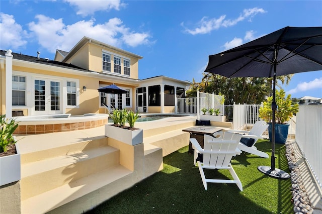 rear view of house featuring a lawn, french doors, a swimming pool, and a sunroom