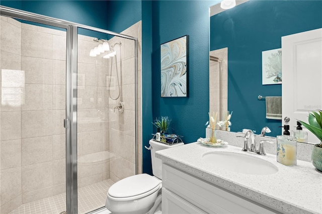 bathroom featuring toilet, vanity, and a shower with shower door