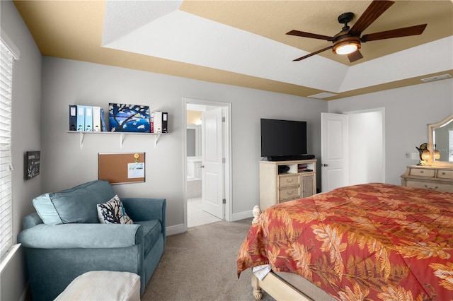 bedroom with light carpet, a tray ceiling, ceiling fan, and ensuite bathroom