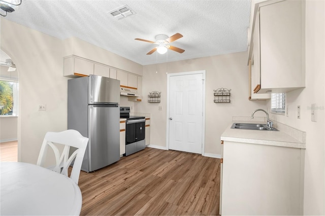 kitchen with sink, ceiling fan, light wood-type flooring, a textured ceiling, and stainless steel appliances