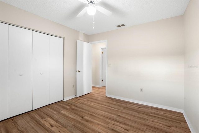 unfurnished bedroom with a textured ceiling, a closet, ceiling fan, and light hardwood / wood-style floors