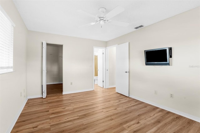 unfurnished bedroom featuring a walk in closet, ceiling fan, a closet, and light hardwood / wood-style floors