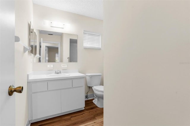 bathroom featuring vanity, wood-type flooring, a textured ceiling, and toilet