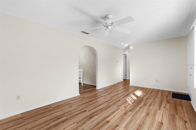 empty room featuring ceiling fan, light wood-type flooring, and a textured ceiling