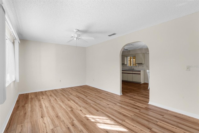 spare room with ceiling fan, sink, light hardwood / wood-style floors, and a textured ceiling