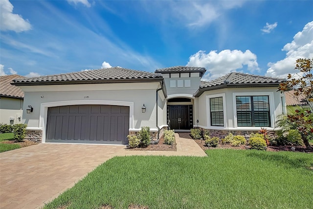 mediterranean / spanish-style home featuring a front yard and a garage