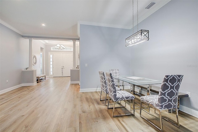 dining space with light hardwood / wood-style floors, an inviting chandelier, ornamental molding, and ornate columns