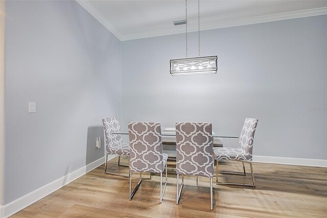 dining room with hardwood / wood-style flooring, ornamental molding, and an inviting chandelier