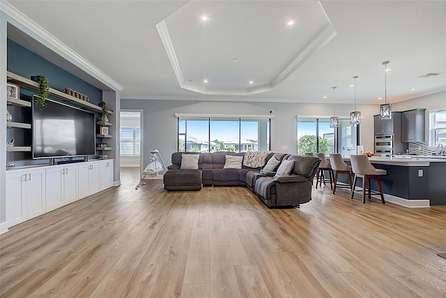 living room featuring a tray ceiling, light hardwood / wood-style flooring, and ornamental molding