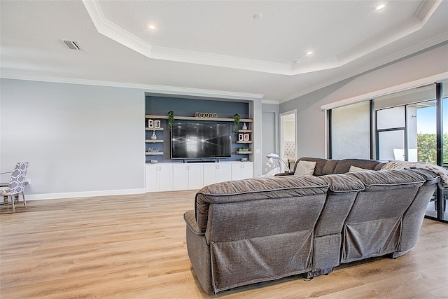 living room with a raised ceiling, crown molding, and light hardwood / wood-style floors