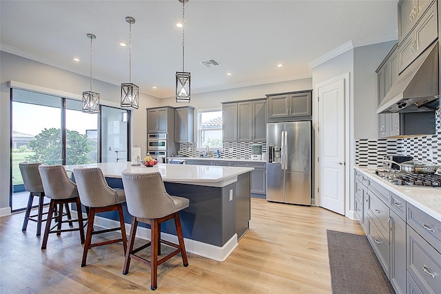 kitchen featuring gray cabinetry, stainless steel appliances, pendant lighting, a kitchen bar, and a kitchen island