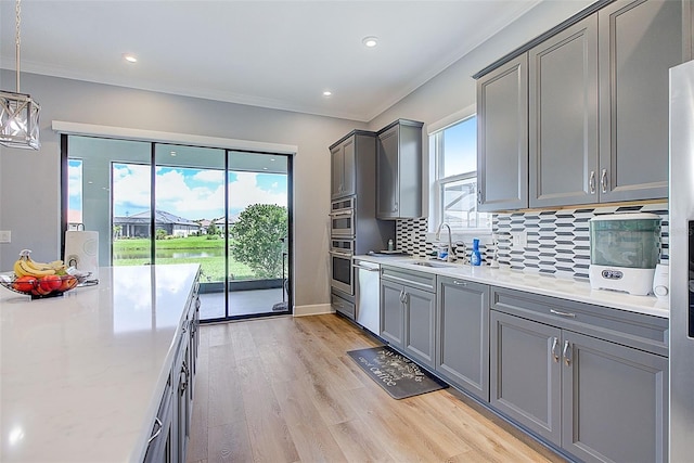 kitchen with plenty of natural light, hanging light fixtures, stainless steel dishwasher, and sink