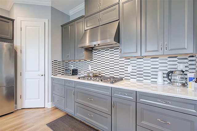 kitchen with appliances with stainless steel finishes, tasteful backsplash, ornamental molding, light hardwood / wood-style flooring, and gray cabinets