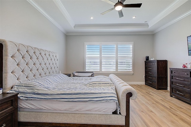 bedroom featuring light wood-type flooring, a tray ceiling, ceiling fan, and crown molding