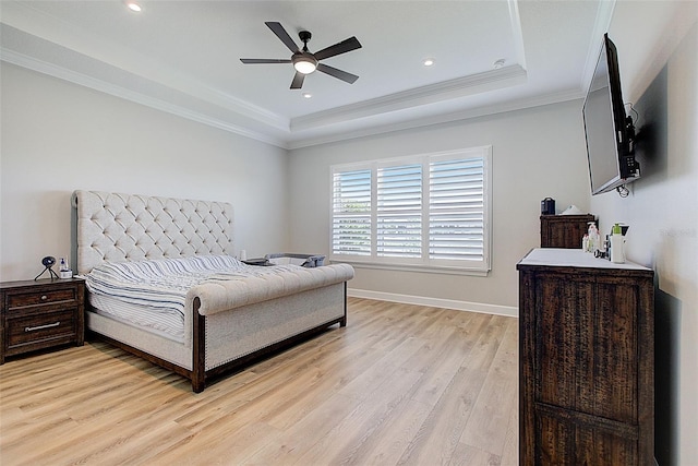 bedroom with light wood-type flooring, a raised ceiling, ceiling fan, and crown molding