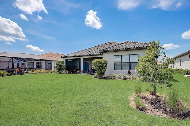 back of property featuring a lanai and a yard