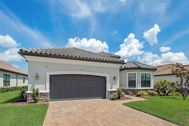 mediterranean / spanish home featuring a front yard and a garage