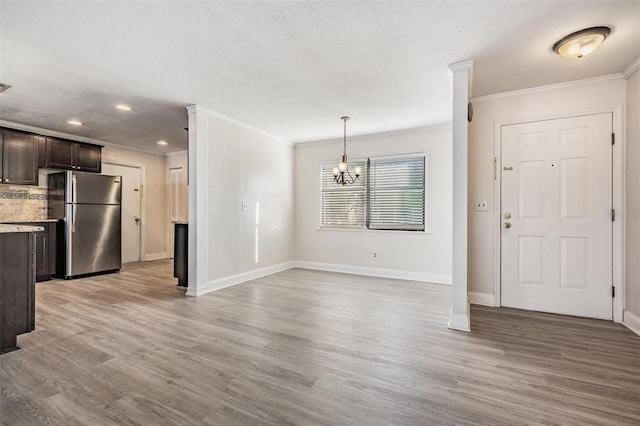 unfurnished dining area with light hardwood / wood-style floors, crown molding, and a notable chandelier