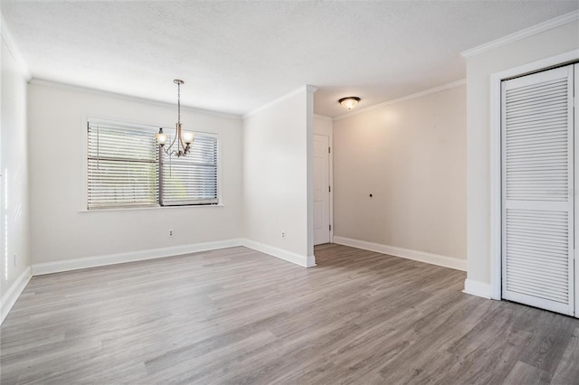 spare room with a textured ceiling, a chandelier, crown molding, and hardwood / wood-style floors