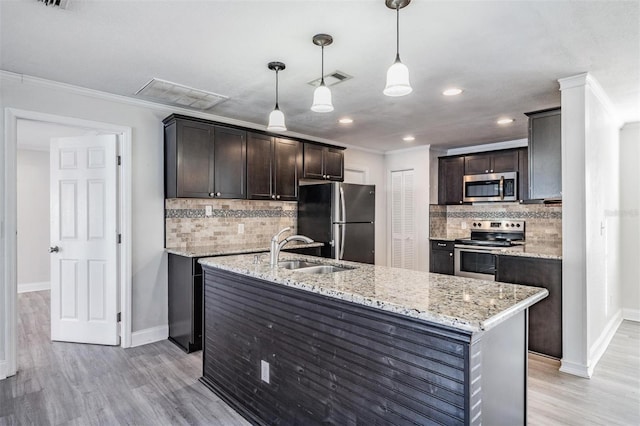 kitchen featuring decorative light fixtures, tasteful backsplash, sink, a kitchen island with sink, and appliances with stainless steel finishes