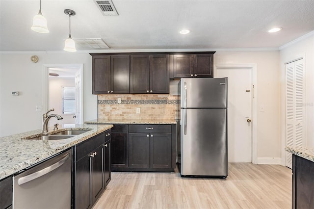 kitchen featuring appliances with stainless steel finishes, dark brown cabinets, hanging light fixtures, and sink