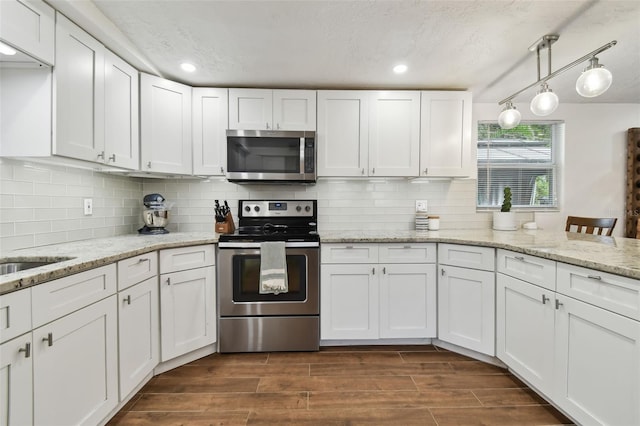 kitchen featuring decorative backsplash, white cabinets, pendant lighting, and appliances with stainless steel finishes