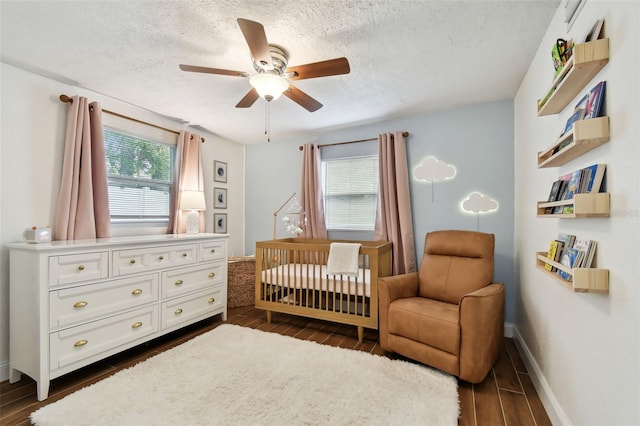 bedroom featuring multiple windows, ceiling fan, a nursery area, and a textured ceiling