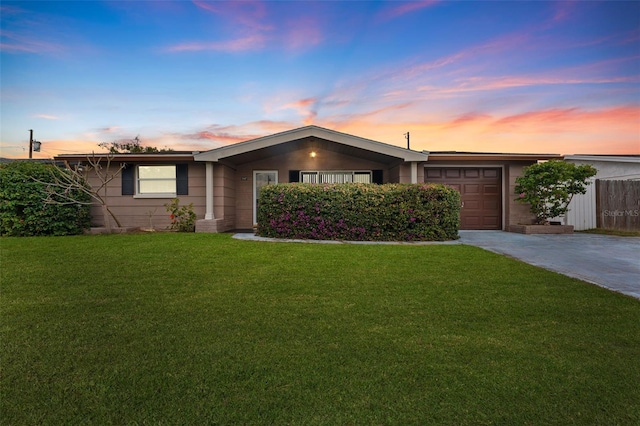 ranch-style home featuring a garage and a lawn