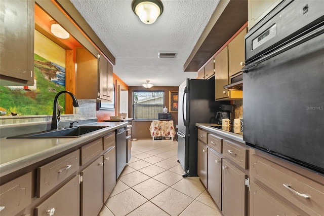 kitchen with sink, a textured ceiling, decorative backsplash, light tile patterned floors, and black appliances