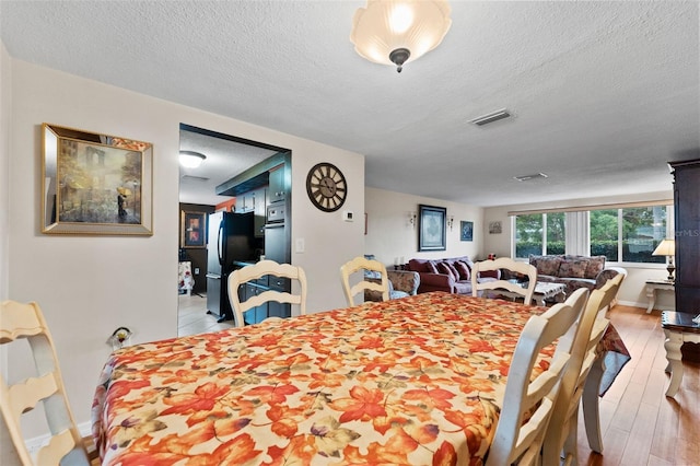 dining room featuring a textured ceiling and light hardwood / wood-style floors