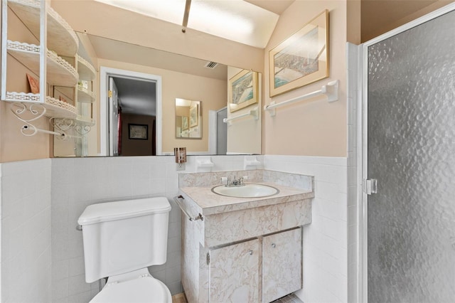 bathroom featuring toilet, vanity, tile walls, and walk in shower