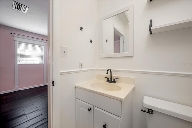 bathroom featuring vanity, hardwood / wood-style floors, a textured ceiling, and toilet