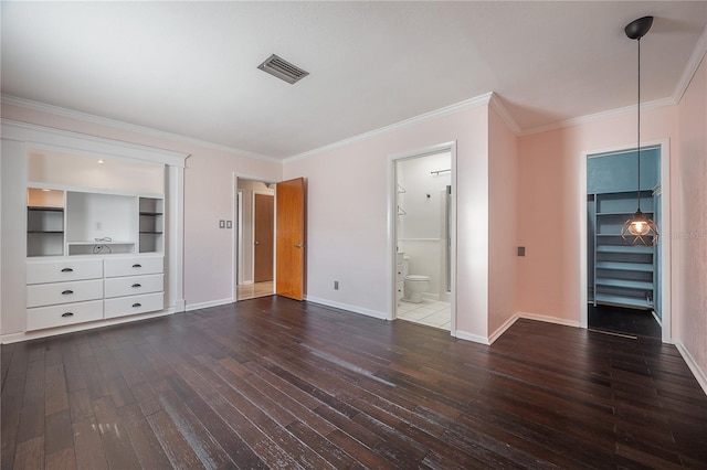 unfurnished bedroom featuring crown molding, ensuite bath, dark hardwood / wood-style flooring, and a spacious closet