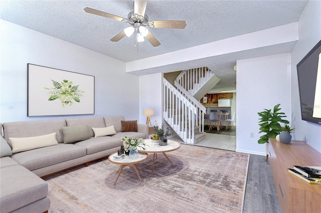 living room with ceiling fan, a textured ceiling, and hardwood / wood-style flooring