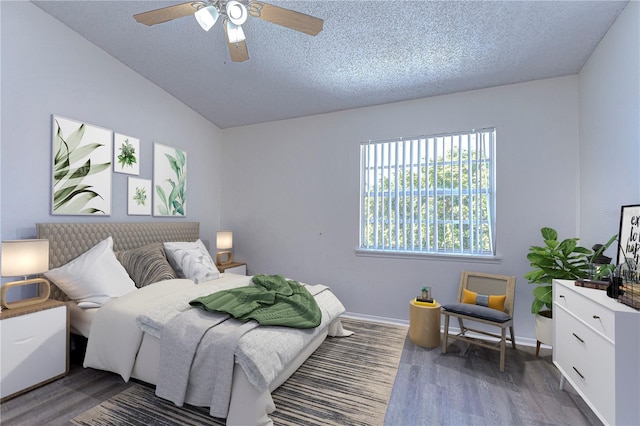 bedroom with a textured ceiling, ceiling fan, dark wood-type flooring, and vaulted ceiling