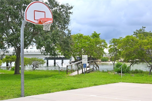 view of basketball court featuring a yard and a water view