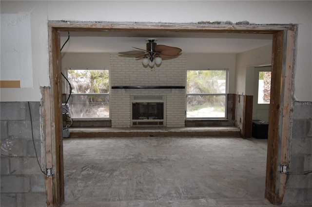 unfurnished living room with ceiling fan, a healthy amount of sunlight, and a fireplace