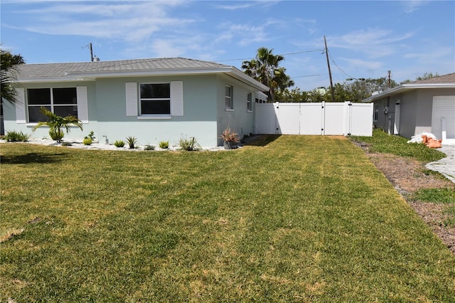 123 9th St, Belleair Beach, FL 33786 - view of home's exterior featuring fence, a lawn, a gate, and stucco siding