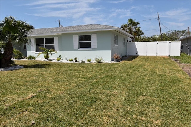 123 9th St, Belleair Beach, FL 33786 - view of property exterior featuring fence, a gate, a yard, and stucco siding