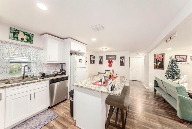 kitchen featuring stainless steel dishwasher, a center island, white cabinets, and sink