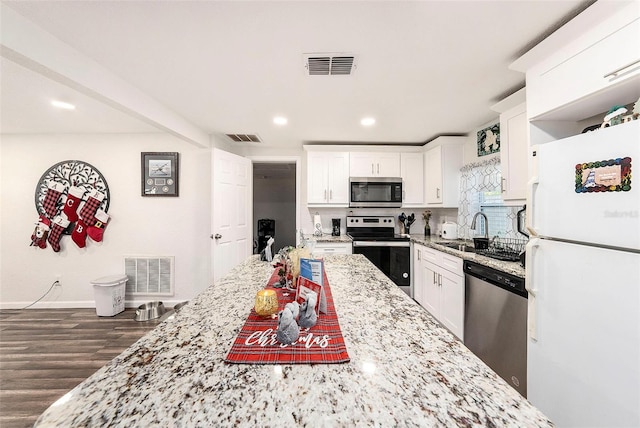 kitchen with sink, light stone countertops, dark hardwood / wood-style flooring, white cabinetry, and stainless steel appliances