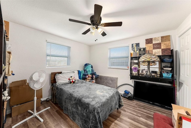 bedroom with multiple windows, ceiling fan, and wood-type flooring