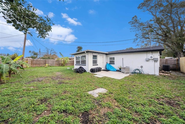 back of property with a patio area, a yard, and central AC