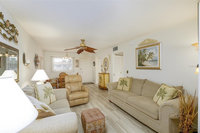 living room featuring ceiling fan, light wood-type flooring, and a textured ceiling