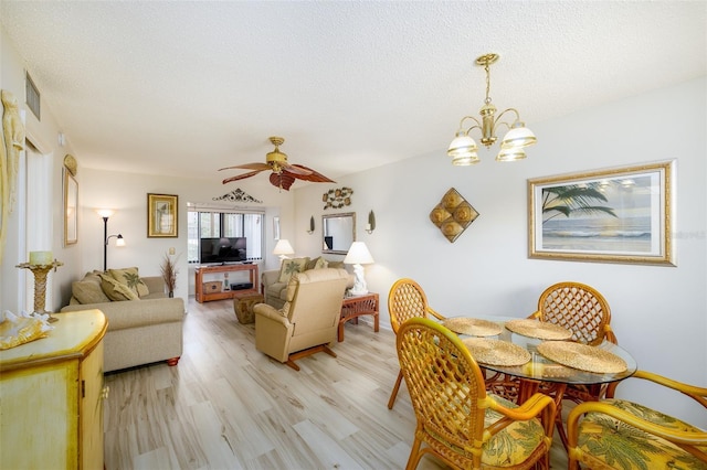 dining space with a textured ceiling, light hardwood / wood-style floors, and ceiling fan with notable chandelier